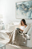 A fresh, white living room featuring a pale tan brown check nz wool throw blanket draped over a model