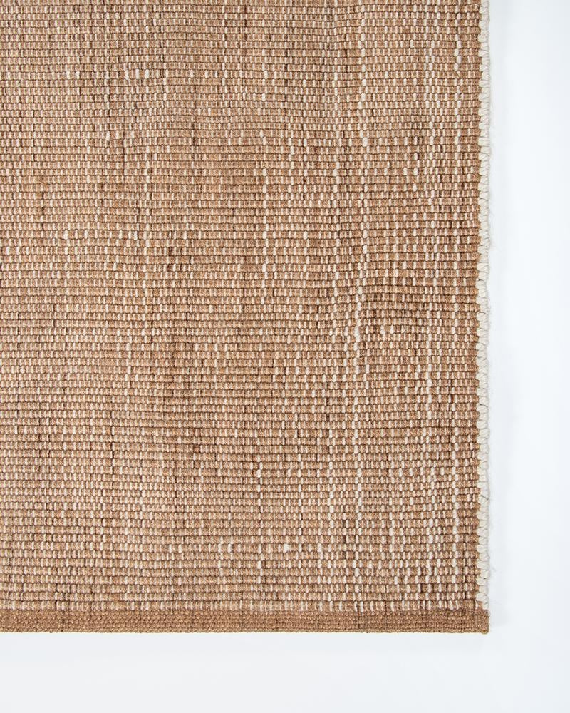 Close up corner of the Londsdale Cumin outdoor rug, showing the white and brown textural weave