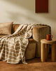 Light brown and white striped throw, draped over a couch, by Weave  Home nz