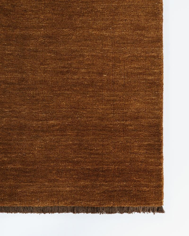 The Baya Sandringham pure wool floor runner rug in Pecan brown, seen at the corner from above highlighting the fringe detail.