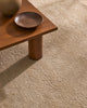 A soft, milky-brown coloured wool rug with a thick, plush pile - the Valencia Dune by Weave Home - seen under a coffee table.