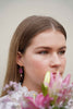 Maroon earrings with gold findings and a freshwater pearl charm, worn by a model