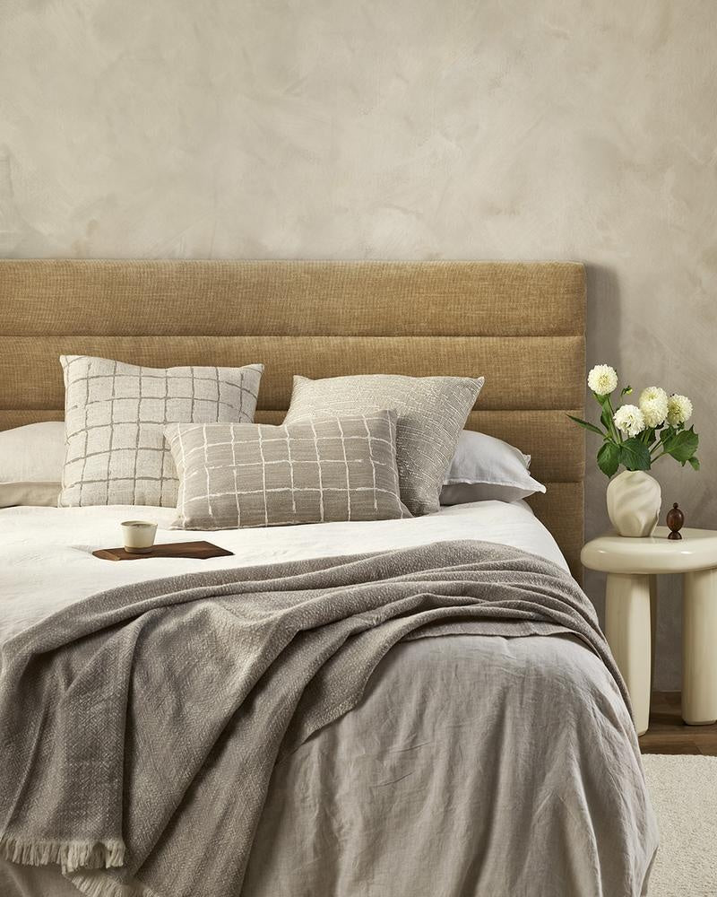 Beautiful cream and beige designer cushions by Baya, on a bed in a stylish modern bedroom.