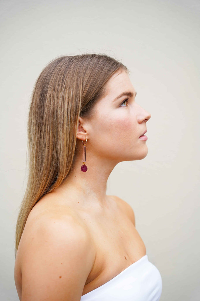 Pink and burgundy dangle earrings by Hagen + Co, worn by a model