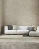 Designer cushions inn brown tones, on a white couch in a modern minimalist living room.