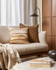 A cream coloured couch with pillows in varying shades of brown, tan, and cream, by Baya. 