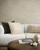 A couch styled with cushions in beige, taupe, cream and camel tones, with highlights of forest green by Baya.