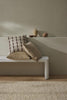 Three stylish cushions, by Weave Home, piled on a bench seat in a modern home.