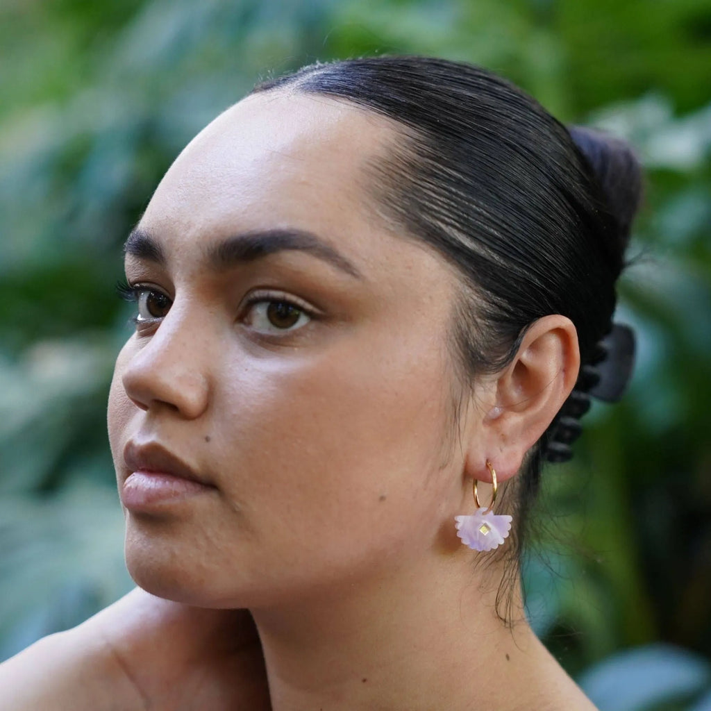 Fantail shaped dangle earrings in a soft lavender purple colour with gold hoops worn by a model