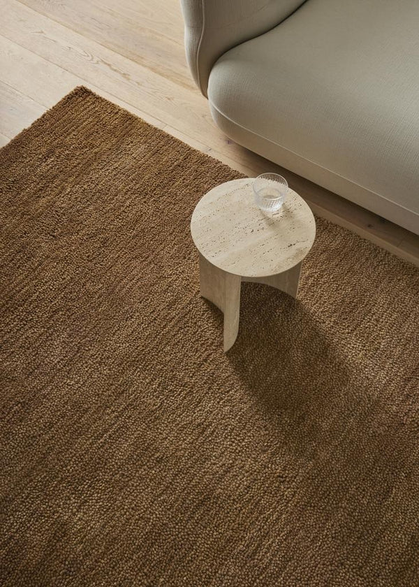 A brown, toffee-coloured wool rug with a thick, plush pile - the Valencia Toffee by Weave Home - seen from above under a coffee table.