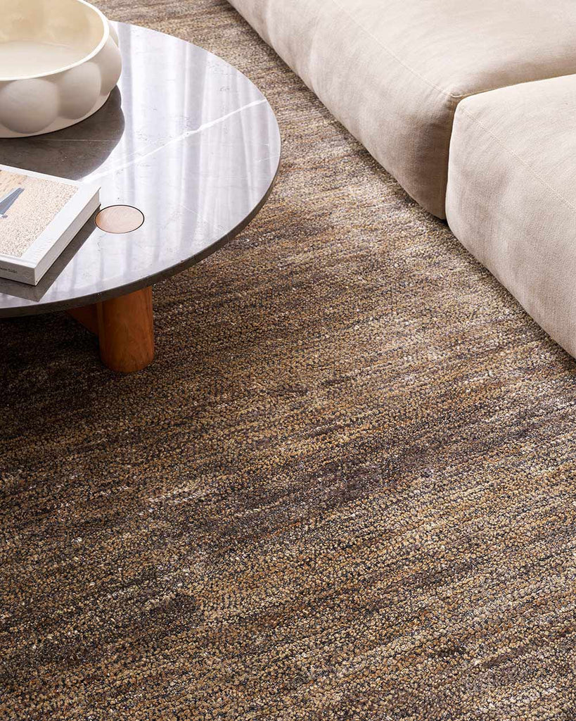 A stylish modern living room with a textural bamboo silk and jute floor rug in shades of warm grey and natural jute brown, by Baya