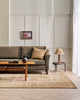 A stylish living room with a soft beige floor rug in sandy warm bamboo silk fibres and natural brown jute, handmade by Baya .