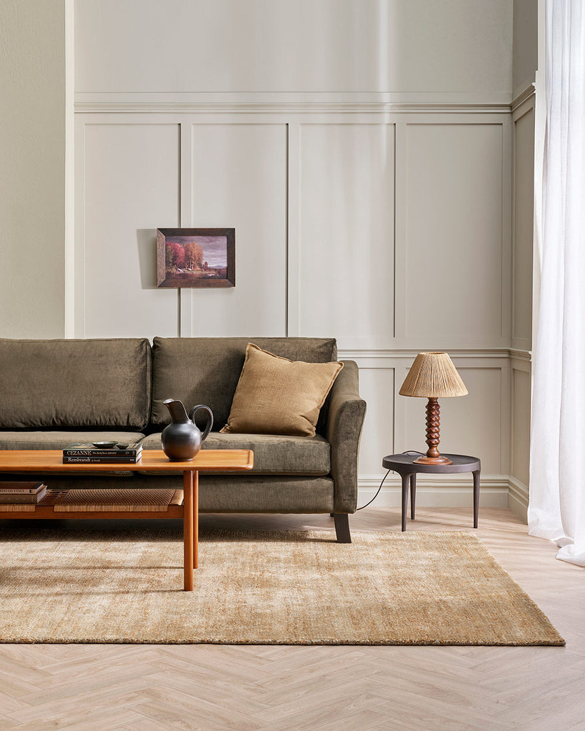 A stylish living room with a soft beige floor rug in sandy warm bamboo silk fibres and natural brown jute, handmade by Baya .