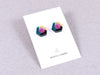 Hexagonal acrylic earrings in pink, teal and gold, by Mystic Forms, on a card