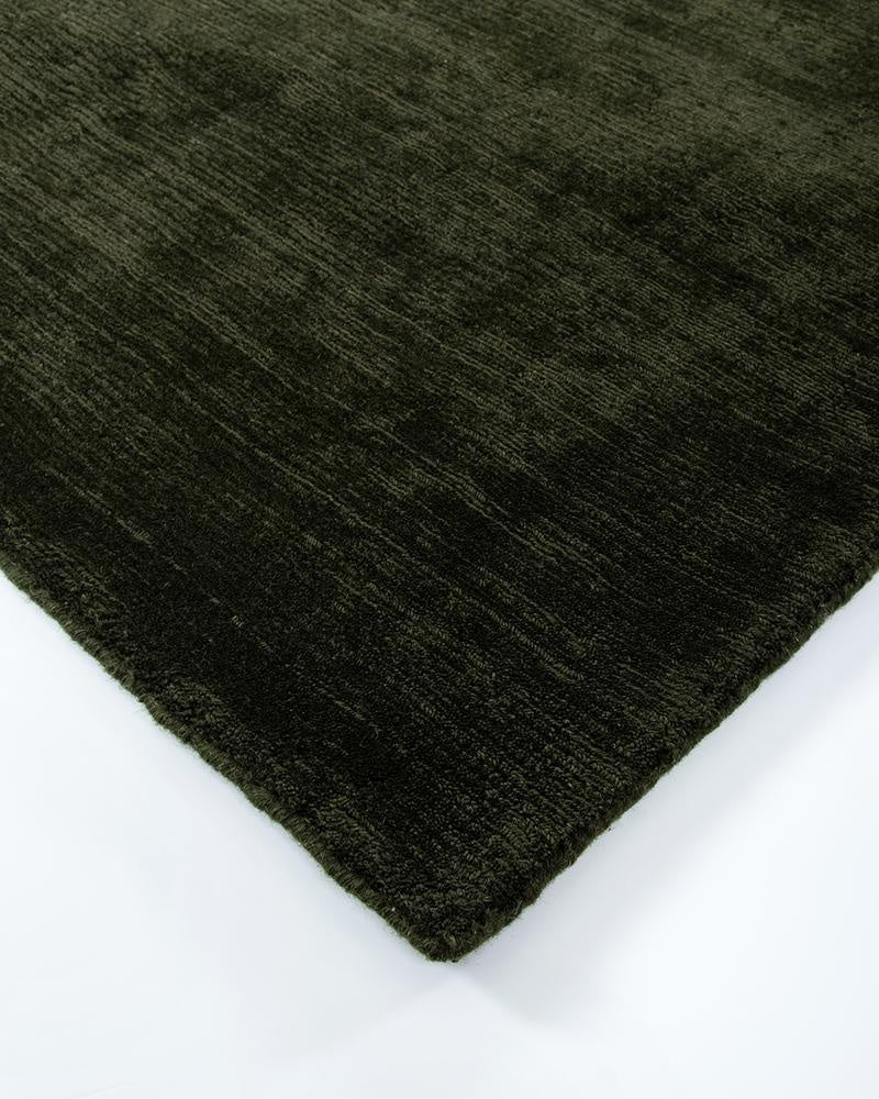 Close up corner shot of the deep green Haywood 'Caper' wool rug showing the sophisticated tip-shearing texture.