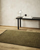 The olive green 'Moss' Sandringham wool runner rug by Baya, seen in a modern home with wooden floorboards.