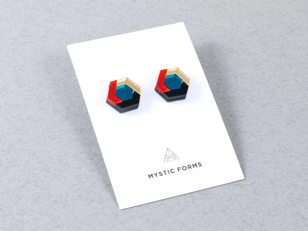 Acrylic, hexagonal stud earrings in teal blue, orange and gold on a card