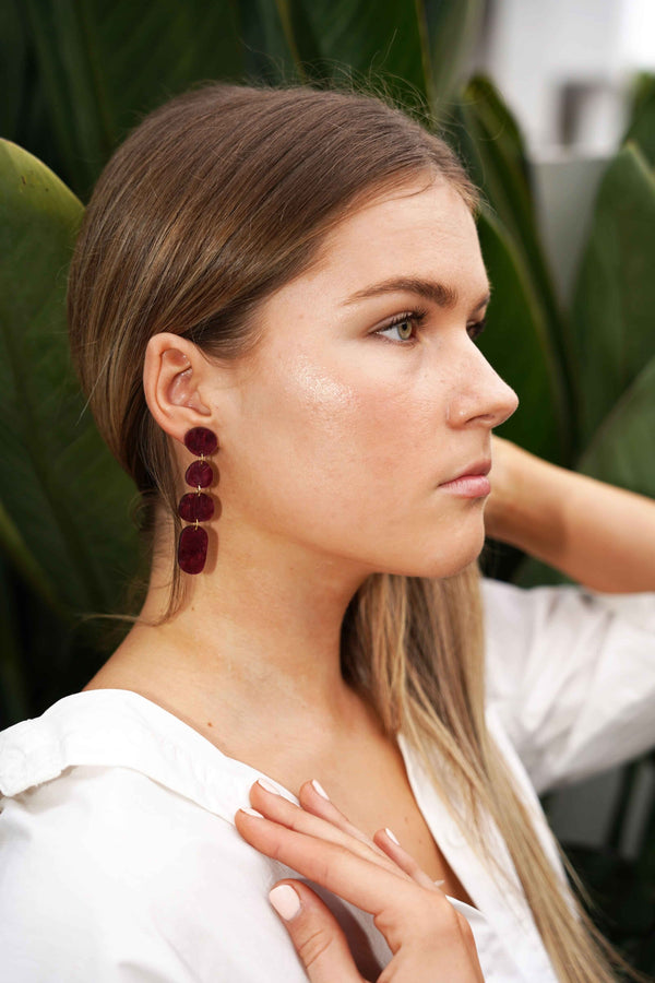 A model wearing burgundy marbled acrylic earrings by NZ designer Hagen + Co