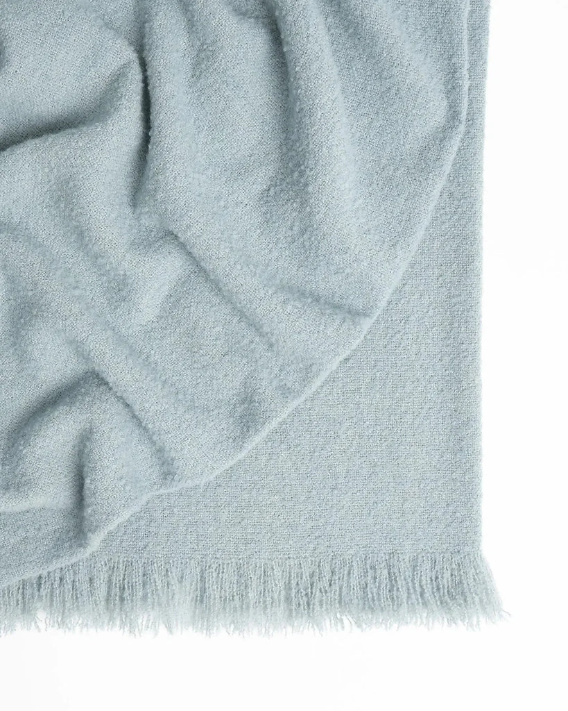 A light blue nz wool throw blanket in a booucle weave, made in NZ