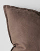 A corner view of a warm chocolate brown linen cushion with a flange edge. 