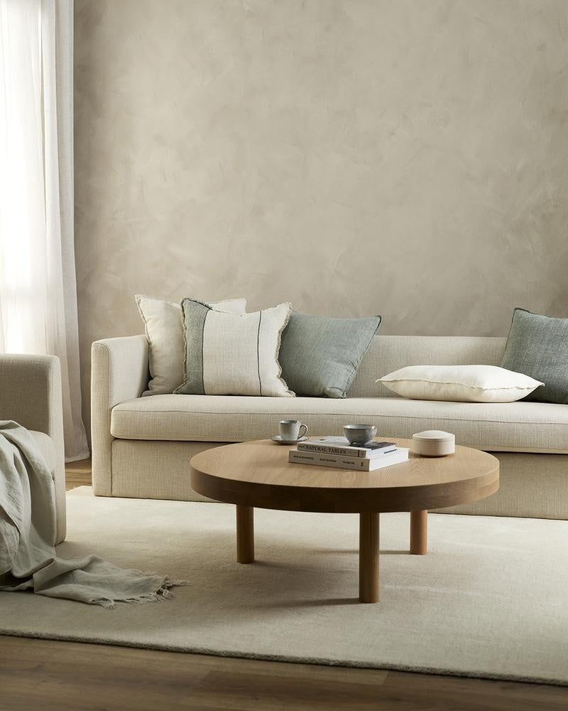 The Baya Flaxmill pure linen cushion in Sage Green in a contemporary living room with complementary cushions.