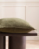 A table with a cushion on it in a deep winter green with a textured linen weave. By Baya