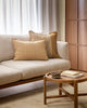 A stylish living room with two cushions, both in tones of soft, warm browns, and one with stripe detailing and a fringed edge.