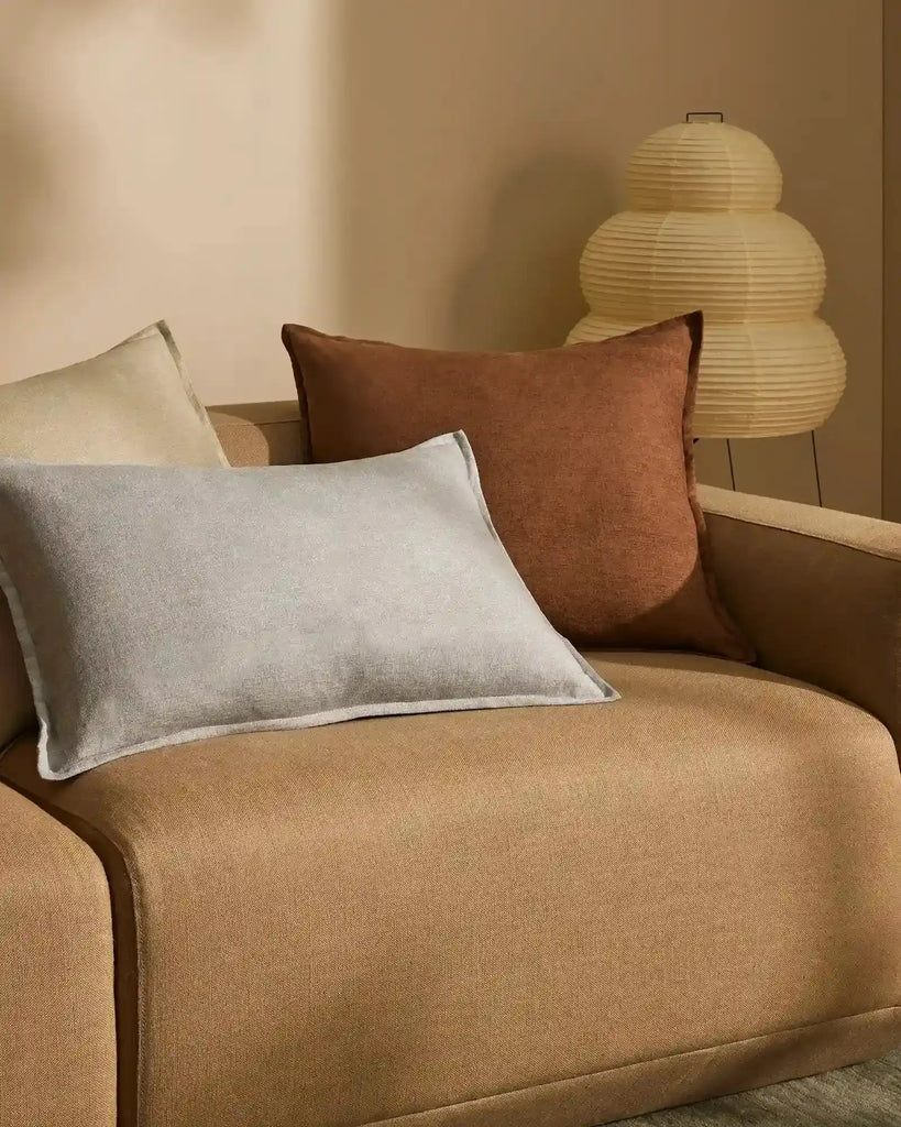 Grey-blue lumbar cushion with flange detail, in chenille and linen blend, on a brown couch