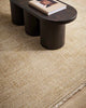 A coffee table on a warm toned beige, lightly distressed 100% NZ wool floor rug with a subtle fringed edge. 