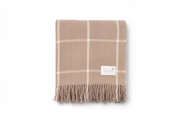 A nz wool throw blanket in a neutral light brown, woven in a tan modern check, by Ruanui Station