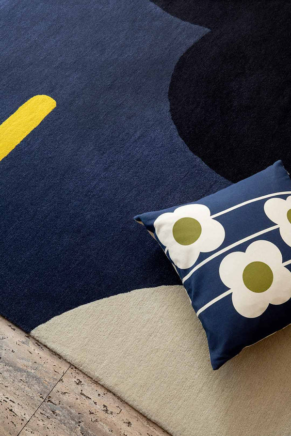 Seen from above, a close up of the 100% wool Orla Kiley geo flower denim blue rug with a pop of yellow and a black flower graphic.