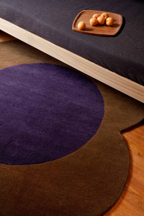The Orla Kiely round Spot Flower 100% wool rug, in colour chestnut brown and violet, seen in on the floor of a modern living room 