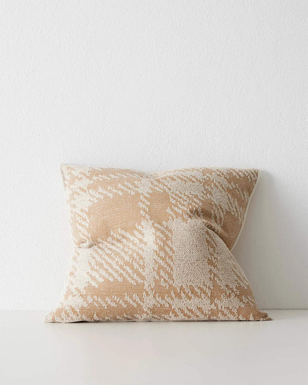 A textured cushion with an oversized check pattern in shades of apricot and cream. 