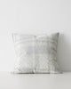 A textured cushion with an oversized check pattern in tones of grey, off white and light blue. 