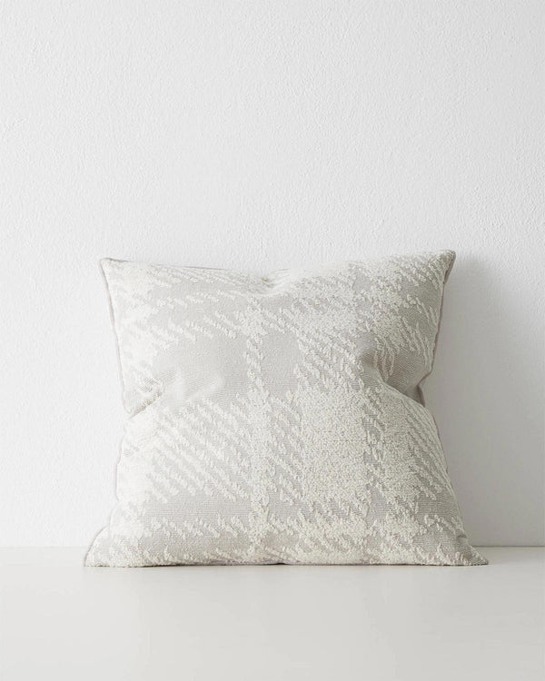 A textural cushion with an oversize check pattern in shades of off-white and soft dove grey. 