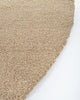 Perspective view of the curved edge of the round Dorset floor rug in light brown, by Baya