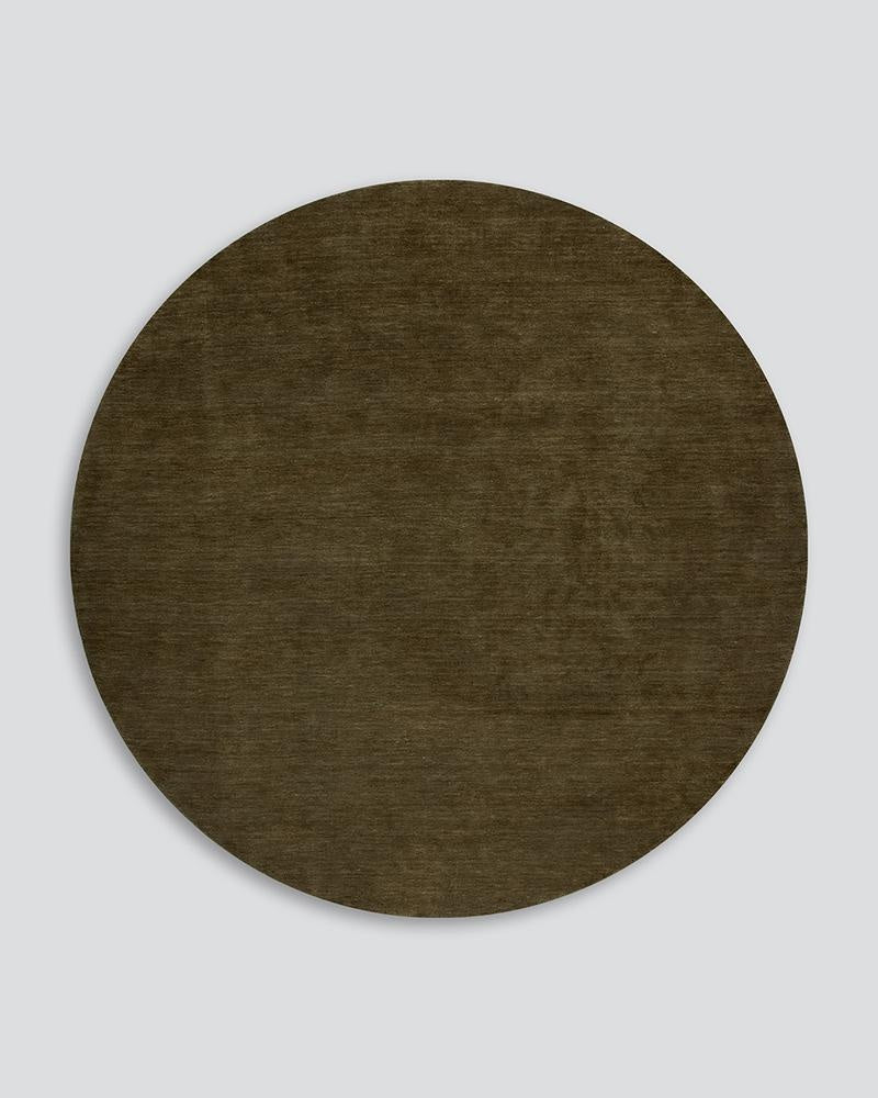 Full view of a mossy-green round wool rug  from above, the Sandringham Moss by Baya