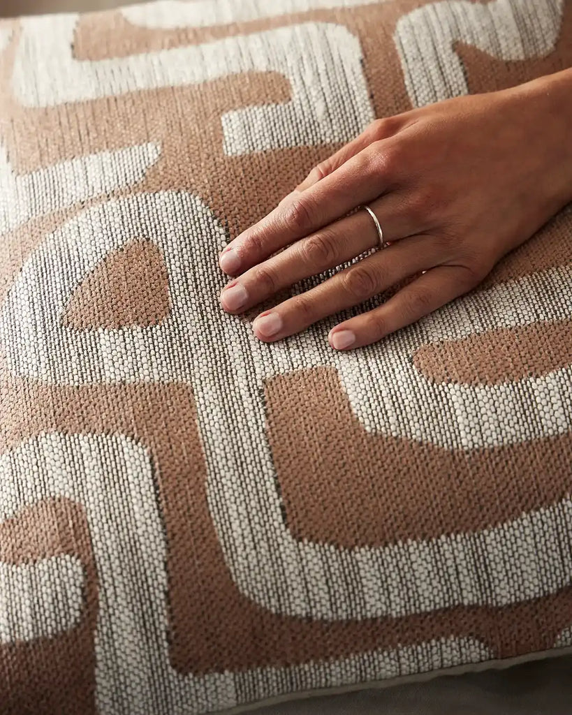 Close up of Weave Home Serene Earth designer cushion in an Ikat weave in earthy brown clay tones