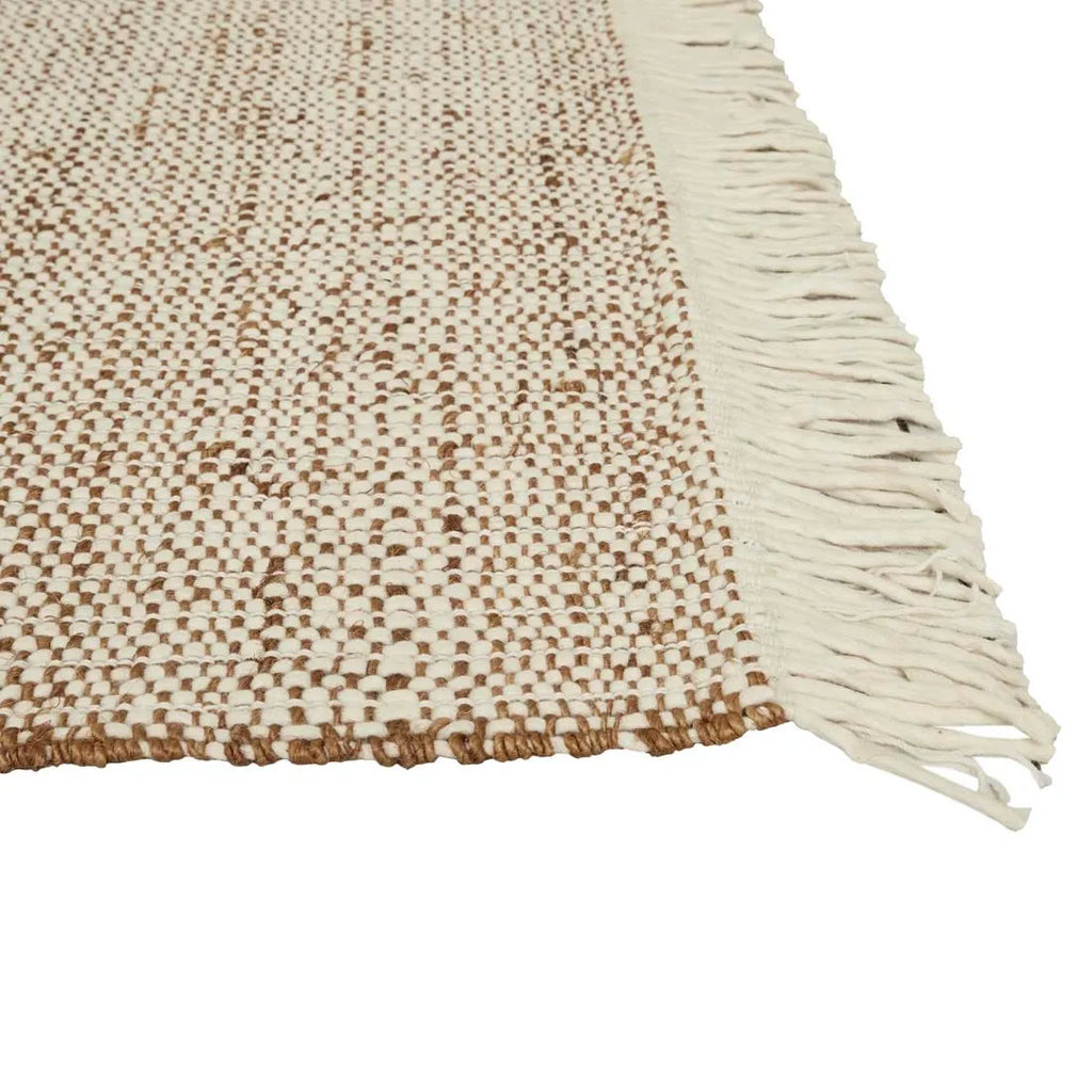 The Tepih Lunan wool and jute blend floor rug in a cream and umber colour, highlighting the cream fringe detail