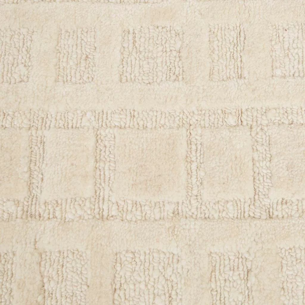 A creamy white wool-blend floor rug featuring an abstract horizontal pattern