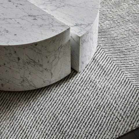 A charcoal and white patterned floor rug seen under a marble coffee table