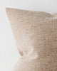 A corner view of a soft textural beige and brown cushion. 