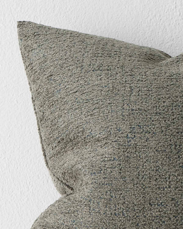 A close up image of a muted moss green cushion with soft elements of texture within the weave. 