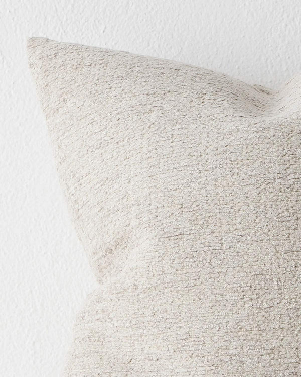 A detailed view of a cool toned cream cushion with soft textured detailing. 