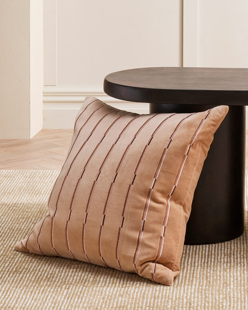 A striped velvet textural cushion in shades of warm, muted clay pink, by Baya. 