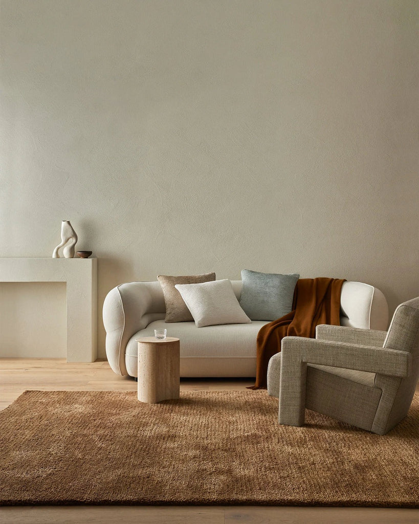 Home decor by Weave Home nz seen in a contemporary home -a wool floor rug, three plush cushions and a wool throw