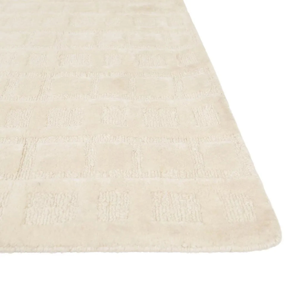 Corner of a creamy white wool-blend floor rug featuring an abstract horizontal pattern, by Globe West and Soren Liv nz