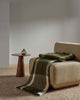 A modern chair with a green and white wool blend throw blanket draped over it. 
