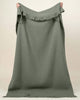 A full image of the Hyde throw blanket, held up to see the soft green shade and generous sizing. 