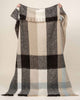 A full image of the Kinloch throw blanket in wool blend with a checked pattern in neutral tones of beige, taupe, brown and blue. 